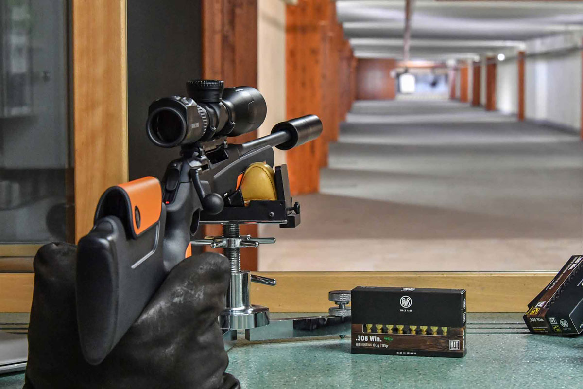Blick aus Sicht eines Schützen im Schießstand über ein Gewehr und einer Verpackung der RWS .308 Win. HIT hinweg 